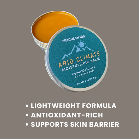 Meridian 100 Arid Climate Moisturizing Balm in a 2 oz round tin, with the lid partially off to show the bright orange balm inside. The lid features a dark teal label with white and gold text. The image has a taupe background. Below the product image is a bullet point list of features in white text. The list reads: 'Lightweight Formula,' 'Antioxidant-Rich,' and 'Supports Skin Barrier.'