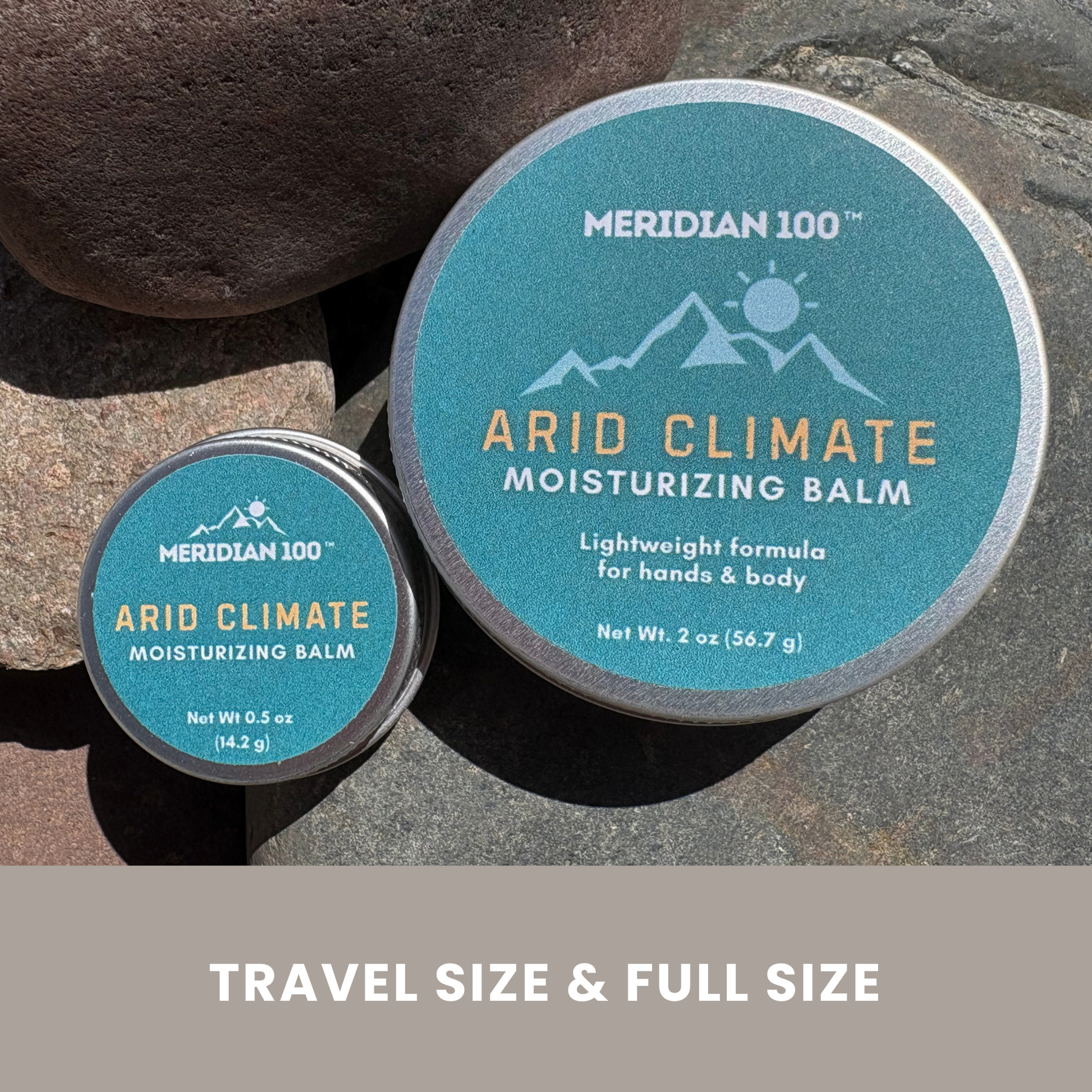 Two round tins of Meridian 100 Arid Climate Moisturizing Balm placed on large rocks outdoors, with one full-size tin and one travel-size tin. A beige banner at the bottom reads 'TRAVEL SIZE & FULL SIZE'.